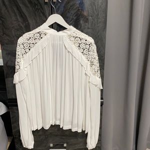 Free People white blouse with raffles around the shoulders.